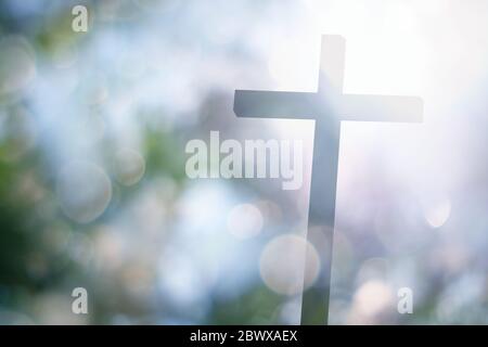 Crucifixion floue de la Croix du Christ avec faisceau de lumière du soleil et beau bokeh. Banque D'Images