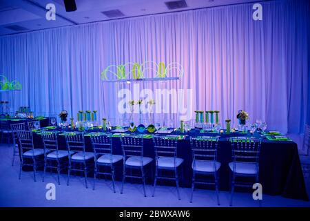 Table longue pour un mariage ou un événement social dans la salle de bal, pièce centrale verte et rouge à la lucite Banque D'Images