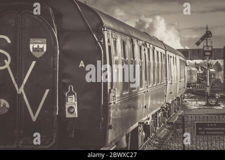 Vue arrière monochrome du train à vapeur britannique d'époque en quittant la gare de Kidderminster, ligne du patrimoine Severn Valley Railway. Trains vintage UK. Banque D'Images