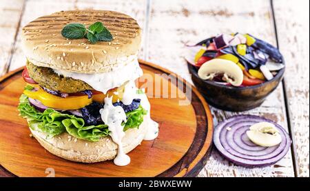 Hamburger végétalien américain, sans gluten, sandwich sans viande et sauce blanche aux herbes. Sandwich au poivre, aux champignons, à la tomate, à la laitue et au prot Banque D'Images