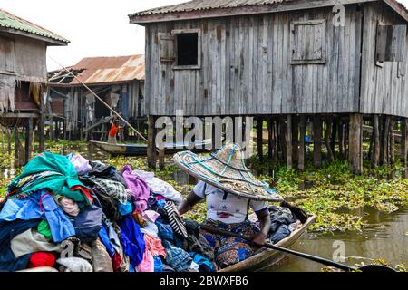 Afrique, Afrique de l'Ouest, Bénin, Lac Nokoue, Ganvié. Un marchand porte des vêtements sur son bateau dans la ville de Ganvié, au bord du lac. Banque D'Images
