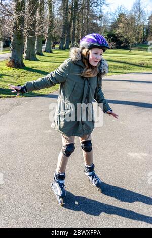 Une jeune fille de treize ans pratiquant sur des rollerbdes dans le parc, Londres, Royaume-Uni Banque D'Images