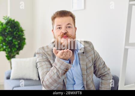 Appel de chat vidéo de rencontres en ligne. Drôle d'homme regarde la caméra en ligne donnant l'air baiser sur une date dans un appel de chat vidéo sur un site de rencontres. Banque D'Images