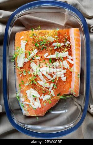 Un morceau de saumon cru servi avec des herbes et des épices dans un plat à pâtisserie en verre sur une serviette beige. Cuisson du saumon, fruits de mer. Menu restaurant, recette. Top vie Banque D'Images