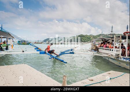 Les capitaines de bateau et leur aide ont mis en place les bateaux à longue queue qui emprennent les touristes vers les lagons, les plages et les îles autour d'El Nido, Palawan, le pH Banque D'Images