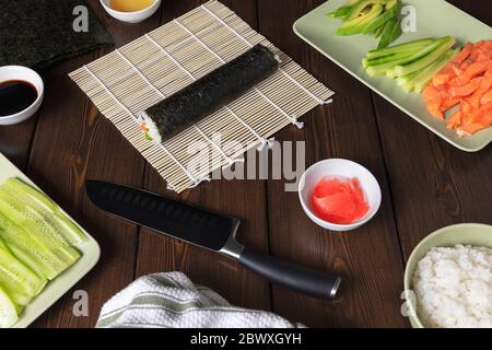 Faire cuire des petits pains à sushis avec du riz, du saumon, de l'avocat, du cucember et du nori à la maison. Nourriture Homemeade. Cuisine maison Banque D'Images