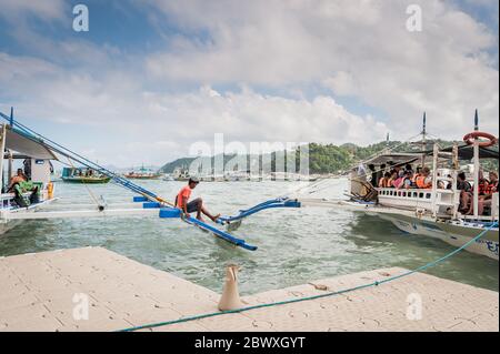 Les capitaines de bateau et leur aide ont mis en place les bateaux à longue queue qui emprennent les touristes vers les lagons, les plages et les îles autour d'El Nido, Palawan, le pH Banque D'Images