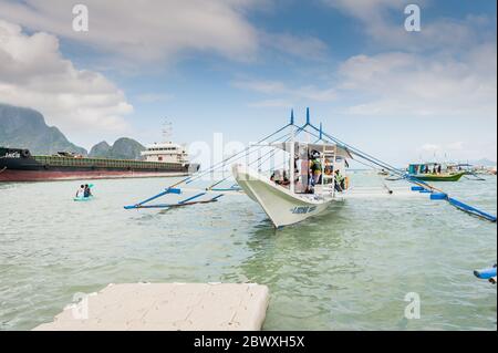 Les capitaines de bateau et leur aide ont mis en place les bateaux à longue queue qui emprennent les touristes vers les lagons, les plages et les îles autour d'El Nido, Palawan. Banque D'Images