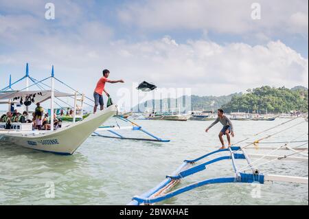 Les capitaines de bateau et leur aide ont mis en place les bateaux à longue queue qui emprennent les touristes vers les lagons, les plages et les îles autour d'El Nido, Palawan, le pH Banque D'Images