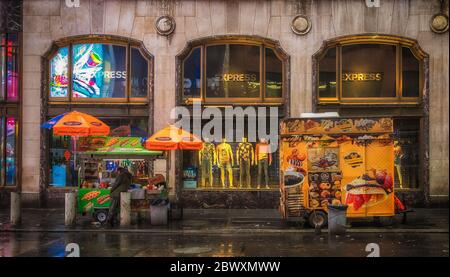 New York City, États-Unis, mai 2019, vendeur de rue devant un magasin de vêtements Express au coin de la 46th St et de Broadway par temps de pluie Banque D'Images