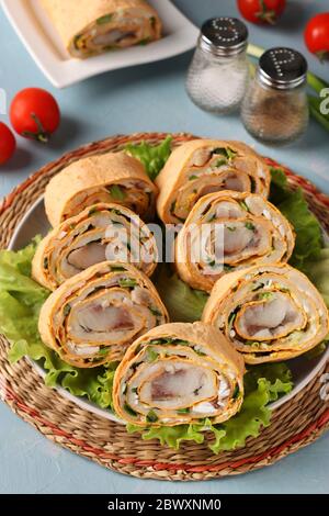 Rouleau de pita avec hareng, pommes de terre et oignons sur fond bleu clair, format vertical, gros plan Banque D'Images