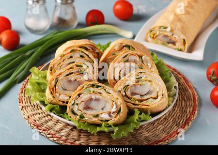 Rouleau de pita avec hareng, pommes de terre et oignons sur fond bleu clair, format horizontal, gros plan Banque D'Images