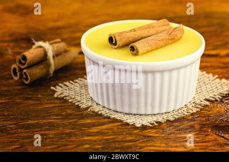 Dessert brésilien sucré crème mousse de maïs fumé à la cannelle sur fond rustique en bois. Banque D'Images