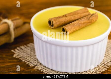 Dessert brésilien sucré crème mousse de maïs fumé à la cannelle sur fond rustique en bois. Banque D'Images