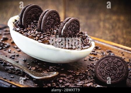 œuf au chocolat blanc typique du brésil, garniture au chocolat blanc et noir crémeux, craquelins oreo et saupoudrées noires. pâques 2020, rustiques de bois de la ba Banque D'Images