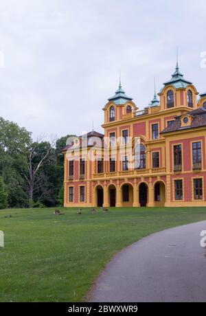 Château de conte de fées rouge et jaune du XVIIIe siècle, « le favori de la perte » à Ludwigsburg, en Allemagne, avec des cerfs sur une pelouse verte Banque D'Images