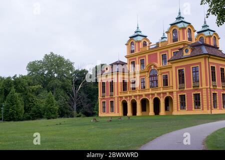 Château de conte de fées rouge et jaune du XVIIIe siècle, « le favori de la perte » à Ludwigsburg, en Allemagne, avec des cerfs sur une pelouse verte Banque D'Images