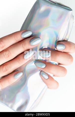 Les mains de jeune femme adulte avec des ongles holographiques à la mode Banque D'Images