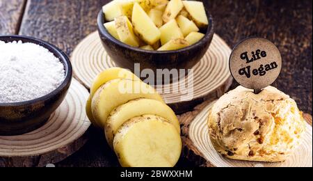 Pain au fromage vegan, fait sans produits animaux, avec des ingrédients sur le côté, du tapioca et des pommes de terre. Panneau en bois avec inscription : vie végétalienne. Banque D'Images