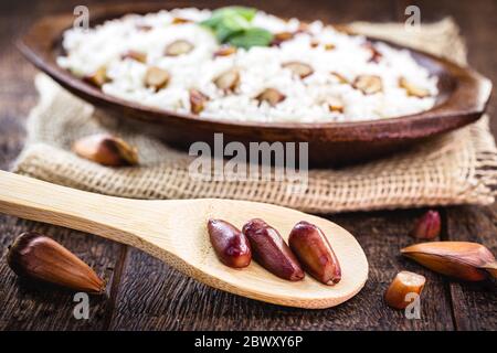 pignons de pin cuits utilisés dans les repas d'hiver. Pignon dans la cuillère avec le riz en arrière-plan, cuisine brésilienne typique, servi chaud. Banque D'Images