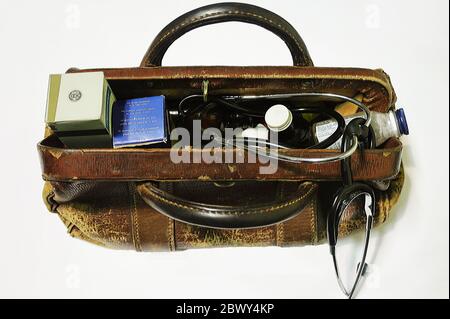 Un vieux sac de médecins en cuir battu contenant un stéthoscope et divers articles de médicaments. Banque D'Images