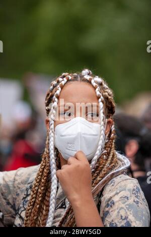 Jeune femme, avec des cheveux tressés, portant un masque facial protecteur, pendant la Black Lives Matter UK Protest march. Londres, Angleterre, Royaume-Uni Banque D'Images