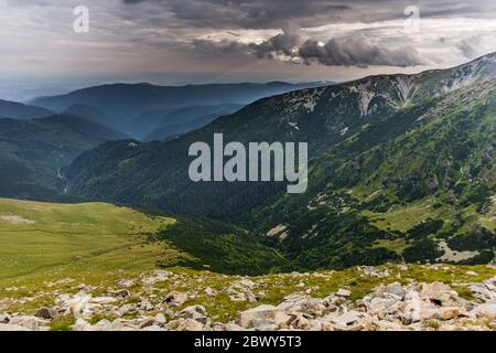 Nuages pluvieux sur la forêt verte d'été dans les montagnes roumaines Parang, vu de la route de Transalpina en Roumanie - la plus haute route de montagne dans Banque D'Images
