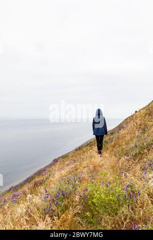 Une jeune femme seule à capuchon sur Ebby Bluff, réserve historique nationale Ebey's Landing, île Whidbey, Washington, États-Unis. Banque D'Images