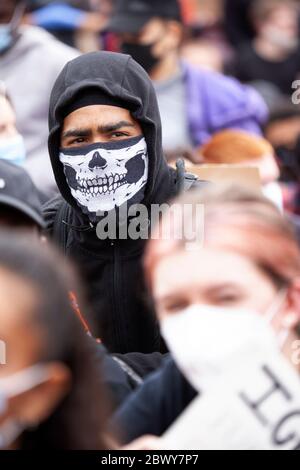 Homme, portant un masque facial à capuche et squelette, assis dans un parc surpeuplé de Hyde Park pendant la Marche de protestation du Royaume-Uni Black Lives Matter. Londres, Angleterre, Royaume-Uni Banque D'Images