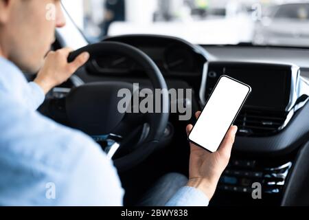 Homme utilisant un smartphone assis en voiture dans Auto Center Banque D'Images
