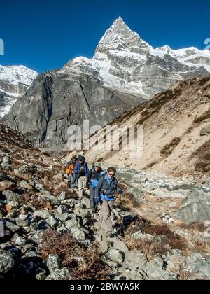 Népal. Partez à Mera Peak. Randonneurs et porteurs sur le sentier de randonnée au-dessus de la colonie de Tagnag avec le fabuleux sommet sans nom sur la rivière Dig gorge. Les paysages de montagne ne sont pas mieux que cela ! Banque D'Images