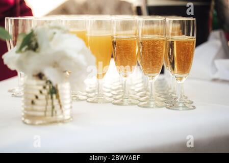 Rangées de verres avec différentes boissons sur une table blanche. Célébration, anniversaire, fête, mariage. Banque D'Images