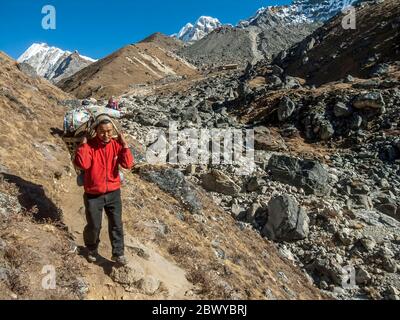 Népal. Partez à Mera Peak. Sentier de randonnée sous la colonie de Khare avec un porteur très chargé en route pour Dignag Banque D'Images