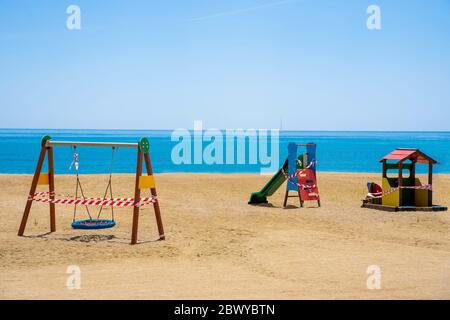 Terrain de jeux fermé sur une plage en raison de la pandémie de COVID-19. Faites pivoter et glissez avec du ruban de protection. Banque D'Images