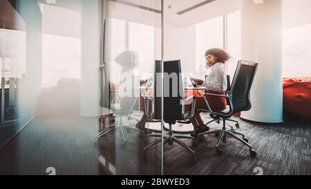 Silhouette d'une femme d'affaires afro-américaine en forme de cheveux bouclés assise sur un fauteuil à l'intérieur d'une salle de réunion de bureau avec réflexion symétrique Banque D'Images