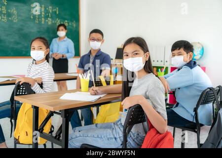 Groupe d'élèves asiatiques du primaire et d'enseignants portant un masque hygiénique pour prévenir l'apparition de Covid 19 en classe pendant la rentrée scolaire reop Banque D'Images