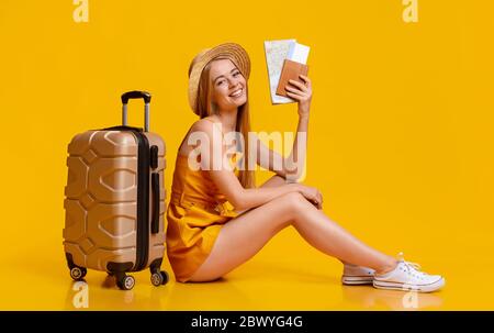 Concept d'assurance voyage. Jeune fille assise sur le sol avec Suitcase et billets Banque D'Images