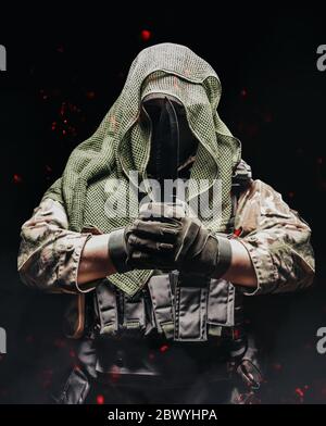 Photo d'un soldat entièrement équipé, camouflé, en foulard en filet tectique avec gilet tactique et gants tenant le couteau des deux mains. Banque D'Images