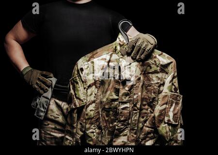 Photo d'un soldat portant une tunique de camouflage multicolore sur fond noir. Banque D'Images