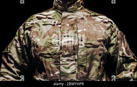 Photo d'un soldat en tunique camouflage multicolore sur fond noir. Banque D'Images