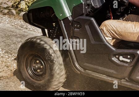 Photo d'un véhicule atv hors route se déplaçant avec le conducteur sur une route poussiéreuse, vue sur les roues. Banque D'Images