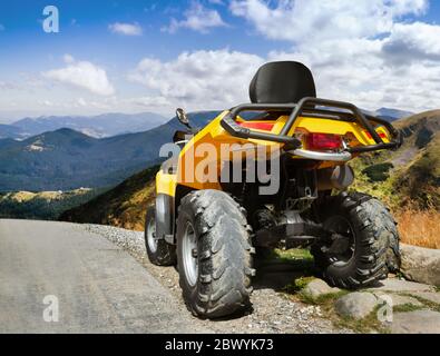 Photo d'un véhicule vtt de tourisme jaune sur une route de montagne vue arrière. Banque D'Images