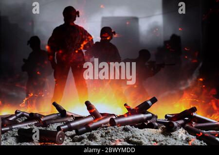 Photo des obus de fusil automatique sur le sable avec le feu et des silhouettes soldats sur fond de champ de bataille. Banque D'Images