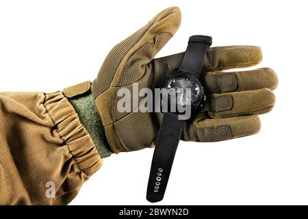 Photo isolée d'un bras de vue de première personne dans une veste tactique et des gants tenant une montre militaire noire sur fond blanc. Banque D'Images