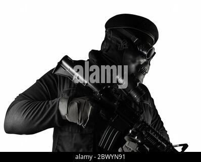 Photo d'un soldat entièrement équipé en gilet d'armure noire debout dans un masque de crâne, un fusil, des lunettes et un béret isolé sur fond blanc vue latérale. Banque D'Images