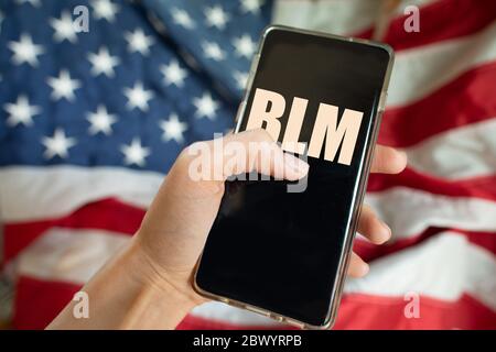 Tenir un téléphone portable avec l'abréviation de Black Lives est important contre le drapeau américain Banque D'Images