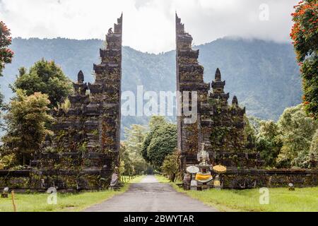 Traditionnel balinais portes séparées candi bentar. Bedugul, Gianyar, Bali, Indonésie. Erythrina variegata ou la griffe de tigre ou les coraux indiens autour. Banque D'Images