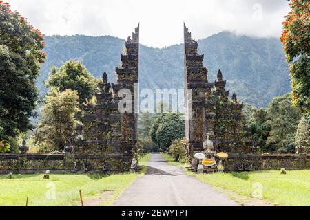 Traditionnel balinais portes séparées candi bentar. Bedugul, Gianyar, Bali, Indonésie. Spathodea Campanulata, ou tulip africains autour. Banque D'Images