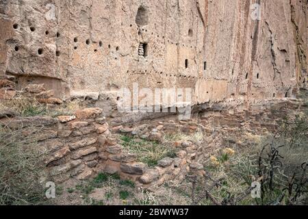 NM00465-00...NOUVEAU-MEXIQUE - fondations anciennes à la base d'une falaise avec des trous forés dans la pierre pour soutenir les toits et les planchers de la maison longue. Banque D'Images