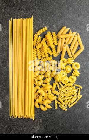 Divers types de pâtes italiennes crues sur table noire. Vue de dessus. Banque D'Images